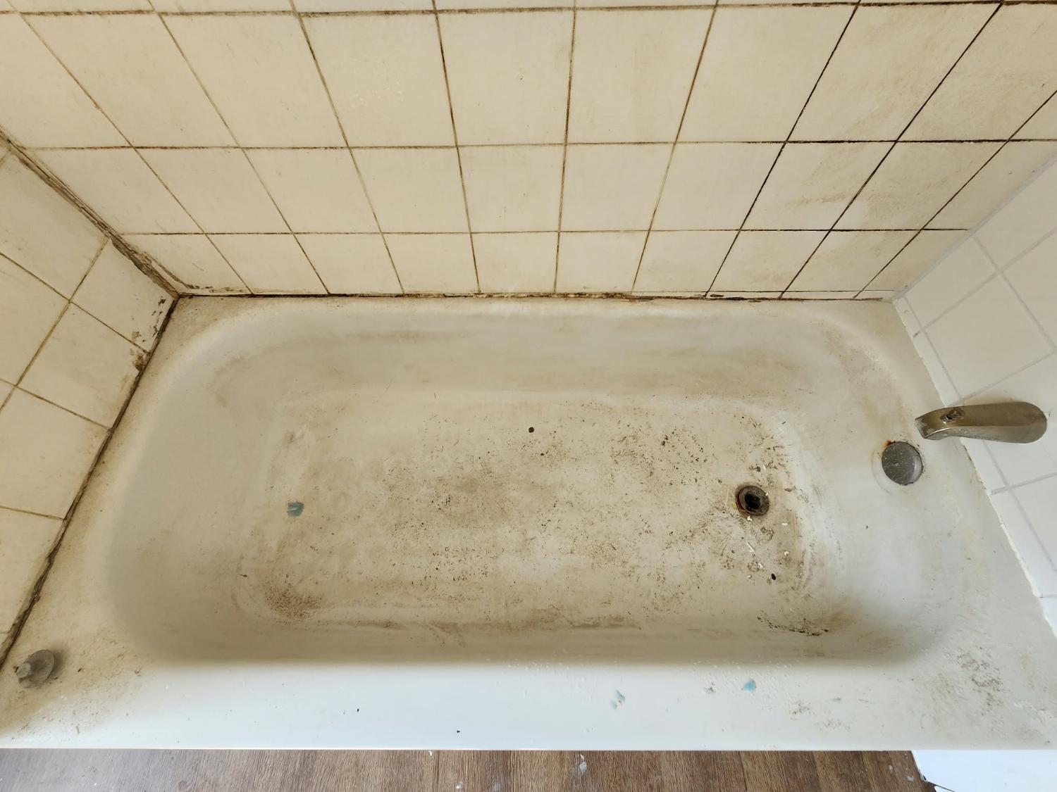 A bathtub with buildup before a deep clean