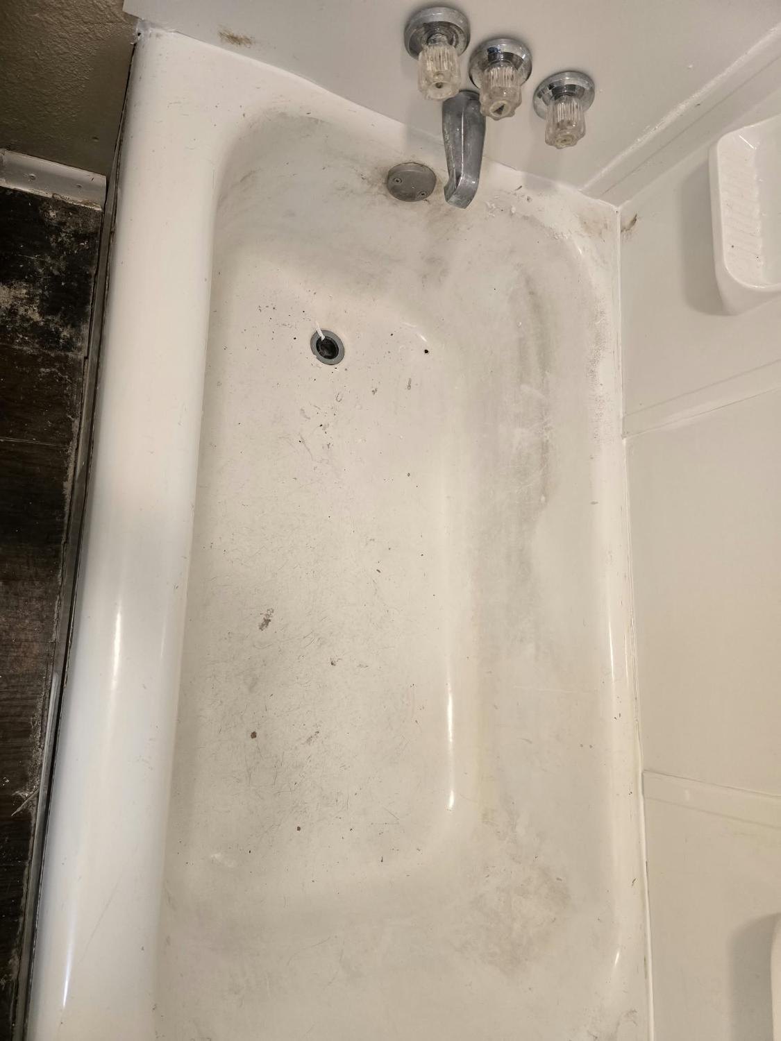 Shower tub with film and debris before cleaning